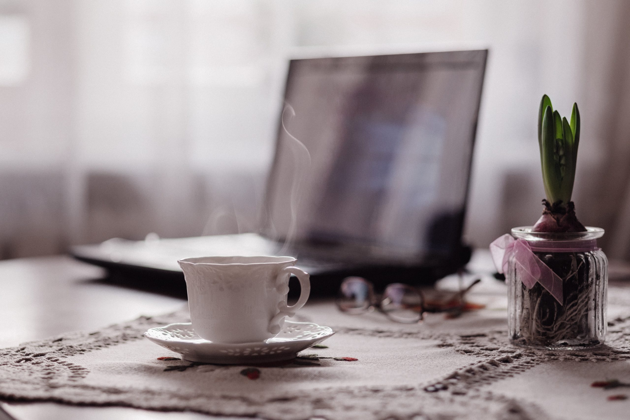 A cup next to a laptop.