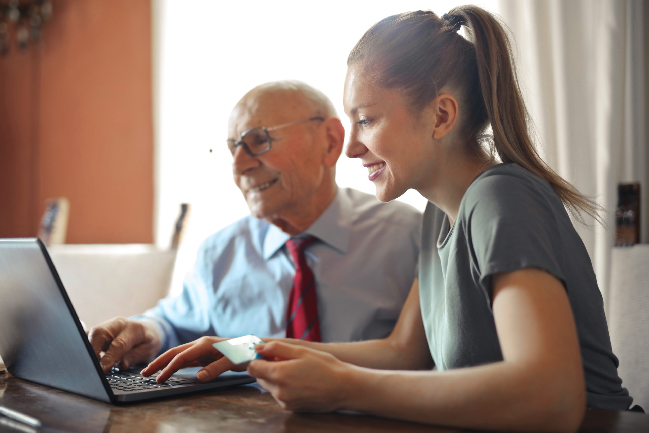 Young woman helping a senior man with payment on internet.