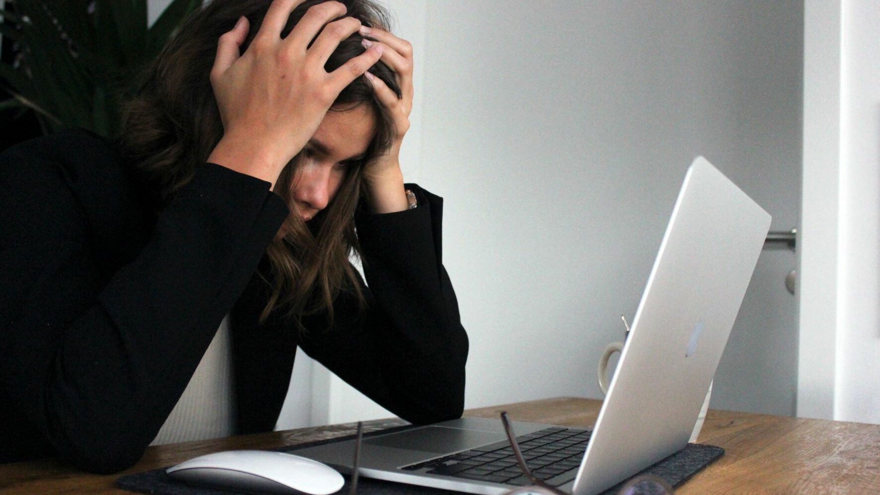 A person looking stressed in front of a laptop.